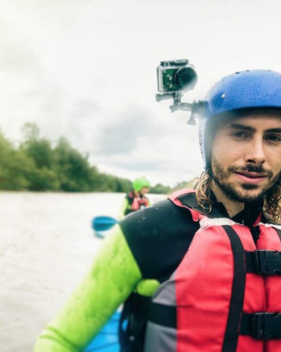 Germany, Bavaria, Allgaeu, portait of confident young man with action cam kayaking on river Iller