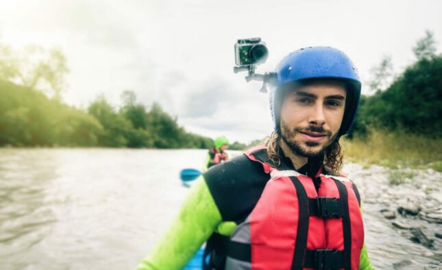 Germany, Bavaria, Allgaeu, portait of confident young man with action cam kayaking on river Iller