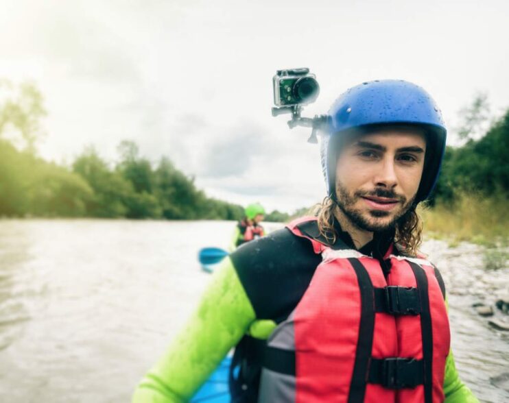 Germany, Bavaria, Allgaeu, portait of confident young man with action cam kayaking on river Iller