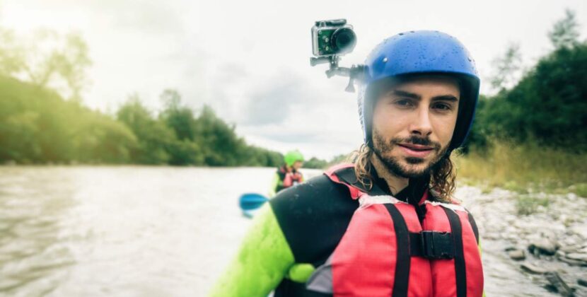 Germany, Bavaria, Allgaeu, portait of confident young man with action cam kayaking on river Iller