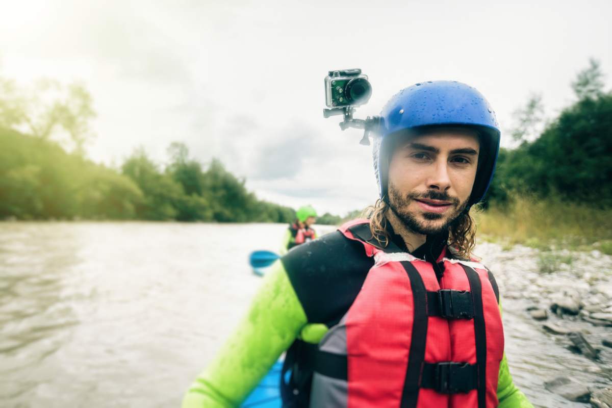 Germany, Bavaria, Allgaeu, portait of confident young man with action cam kayaking on river Iller