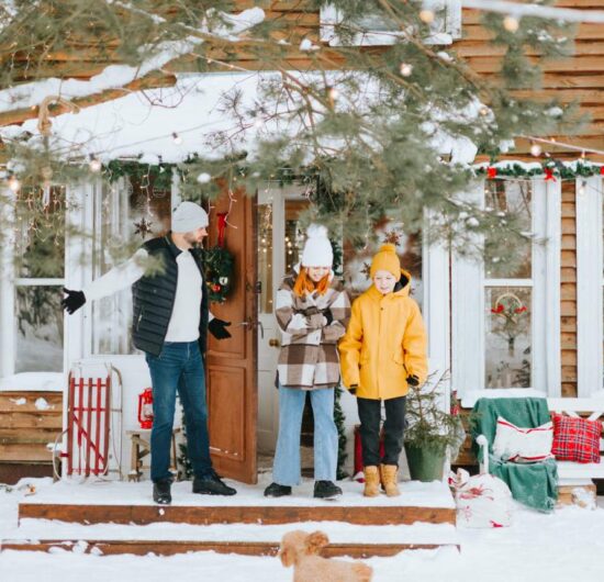 family dad and siblings teenage boy and girl near front door porch of village countryside house with swing hammock decorated for Christmas winter holidays, Christmas and New year vacation concept