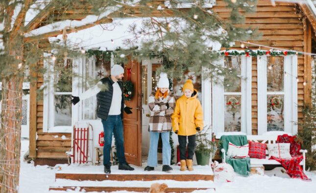 family dad and siblings teenage boy and girl near front door porch of village countryside house with swing hammock decorated for Christmas winter holidays, Christmas and New year vacation concept