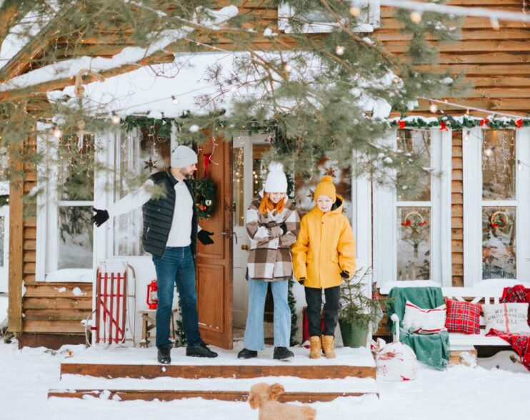 family dad and siblings teenage boy and girl near front door porch of village countryside house with swing hammock decorated for Christmas winter holidays, Christmas and New year vacation concept