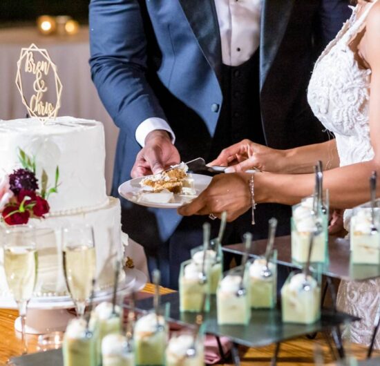 The bride and the groom cutting the beautiful white wedding cake - wedding catering concept