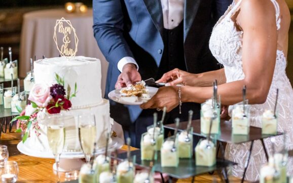 The bride and the groom cutting the beautiful white wedding cake - wedding catering concept