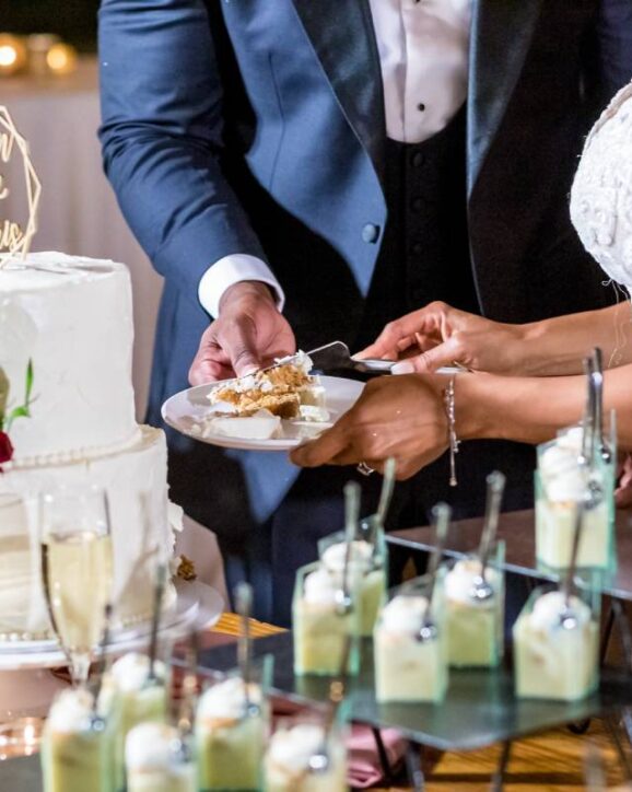 The bride and the groom cutting the beautiful white wedding cake - wedding catering concept