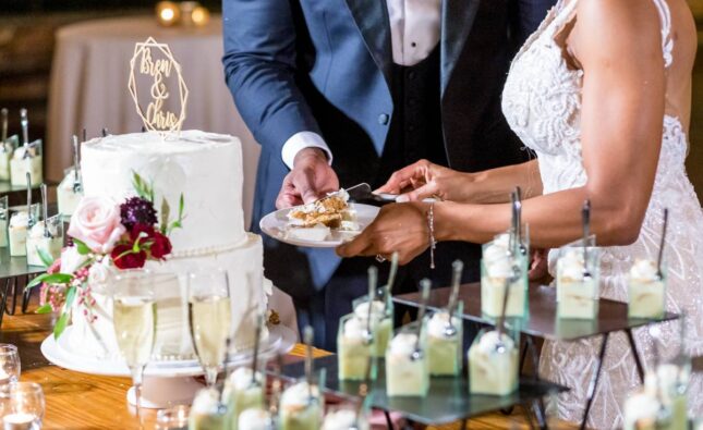 The bride and the groom cutting the beautiful white wedding cake - wedding catering concept