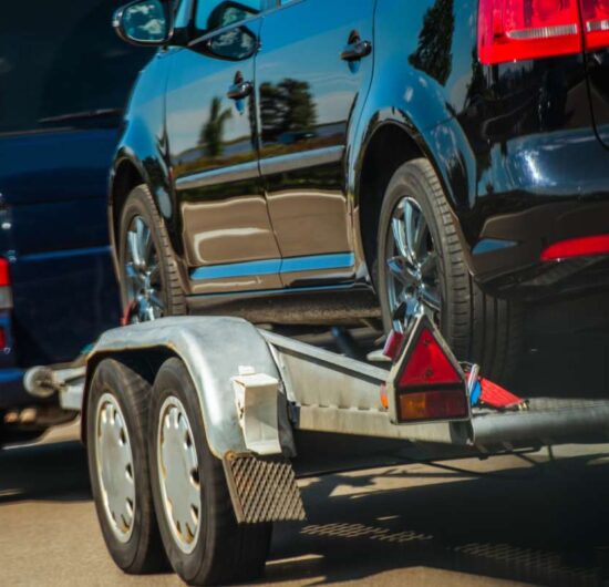 Used Cars Importing in European Union. Van Pulling Trailer with Damaged Pre Owned Vehicle For Sale in Other Country.
