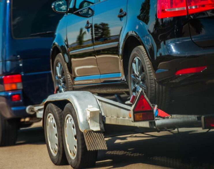Used Cars Importing in European Union. Van Pulling Trailer with Damaged Pre Owned Vehicle For Sale in Other Country.