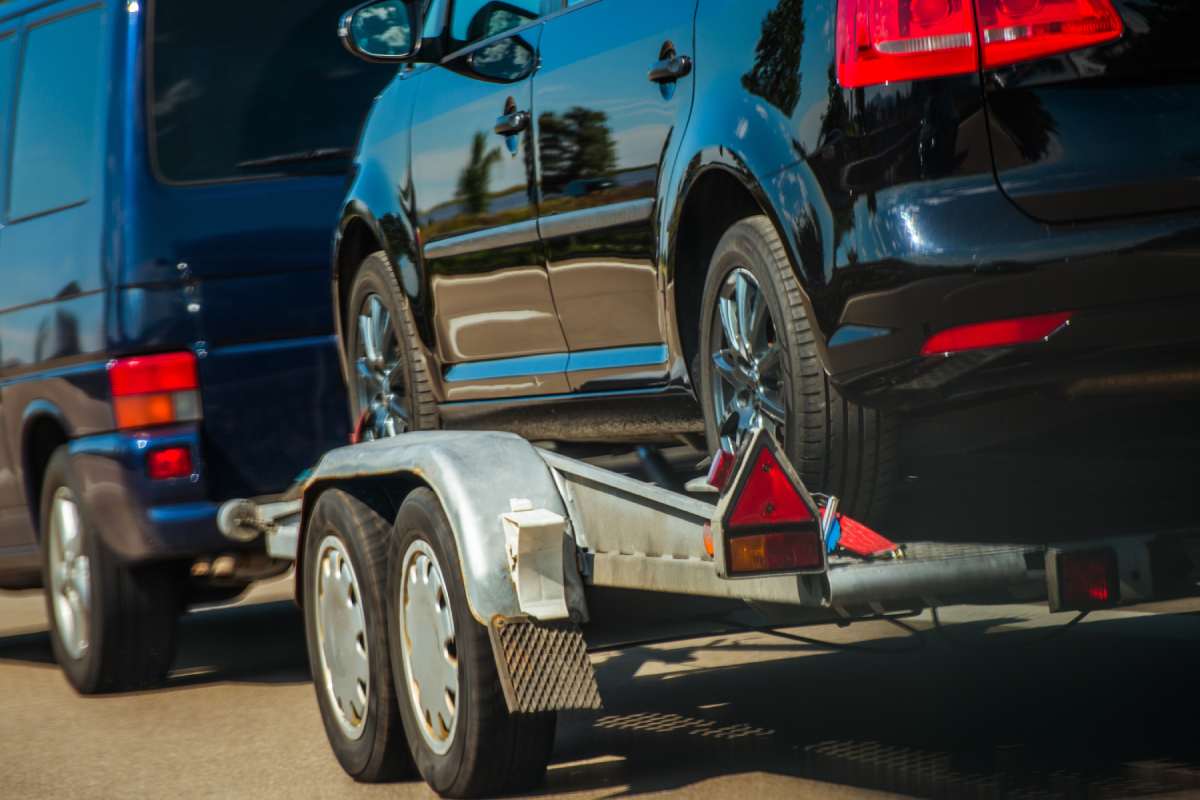 Used Cars Importing in European Union. Van Pulling Trailer with Damaged Pre Owned Vehicle For Sale in Other Country.